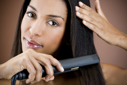 A young woman straightening her hair